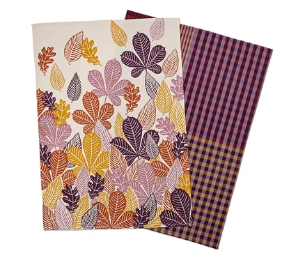 Deux torchons sont posés l'un sur l'autre. L'un a un imprimé de feuilles et l'autre un motif à carreaux.