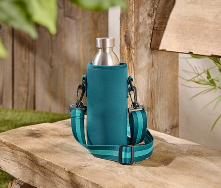 Une bouteille en acier inoxydable dans un étui turquoise avec une bandoulière est posée sur un banc en bois.