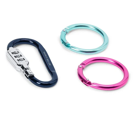 Gros plan d'un mousqueton bleu avec un cadenas à combinaison et de deux mousquetons ronds turquoise et rose sur un fond blanc.