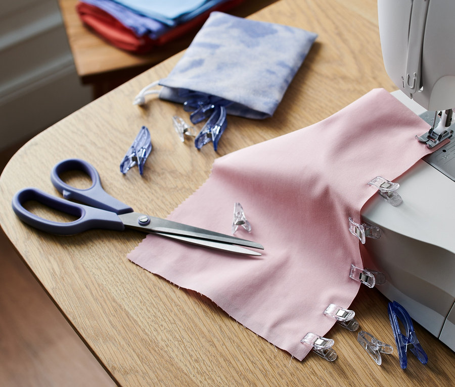 Tissu rose avec 20 pinces à tissu sur une machine à coudre.