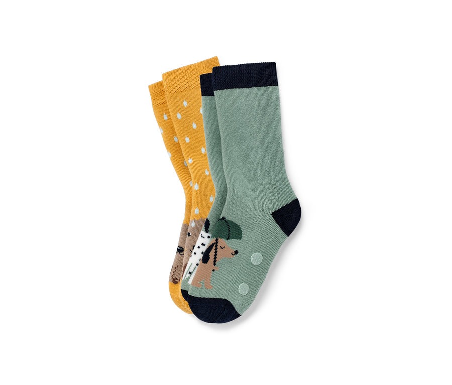 Deux paires de chaussettes anti-dérapantes pour enfant : une paire moutarde à pois blancs et une paire verte avec un motif de chien.