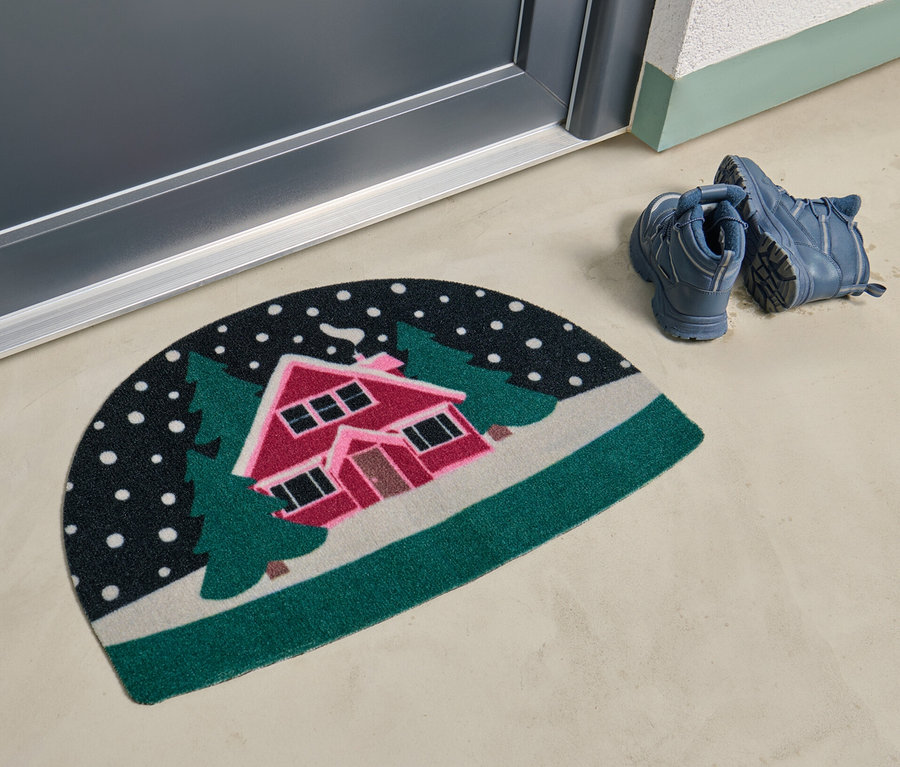 Un paillasson avec un motif de paysage enneigé se trouve devant une porte.