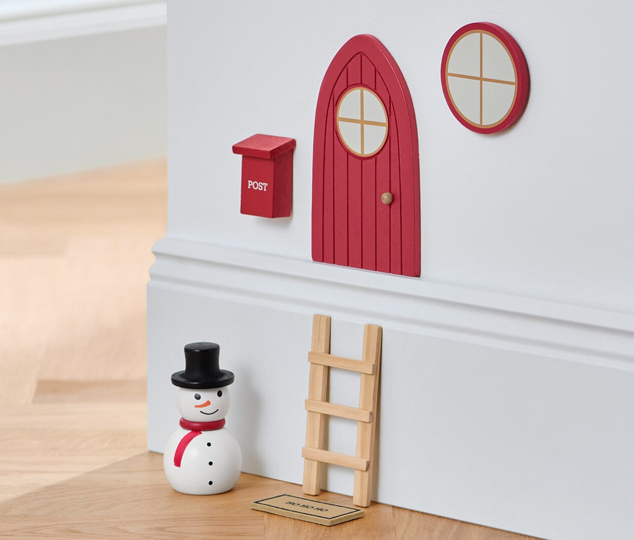 Un set porte de lutin sur un mur avec un bonhomme de neige et un tabouret.