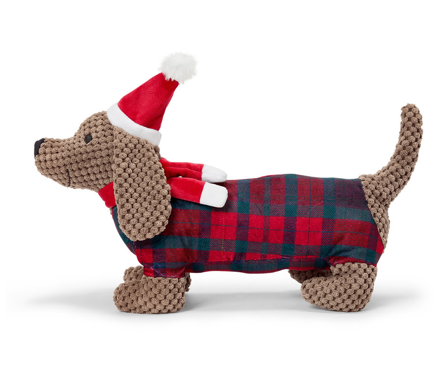 Un teckel en peluche marron avec une couverture à carreaux et un bonnet de Noël.