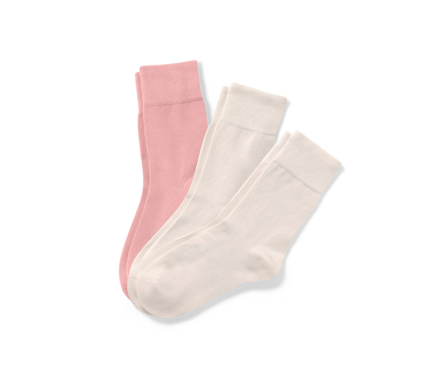 Trois paires de chaussettes claires sont posées sur un fond blanc.