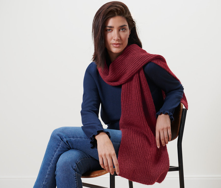 Femme assise sur une chaise portant une écharpe en maille avec de la laine.