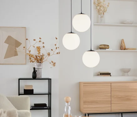 Salon avec table basse ronde, console design avec compartiments en verre et lampes à suspension avec globes en verre, 3 flammes, rondes.