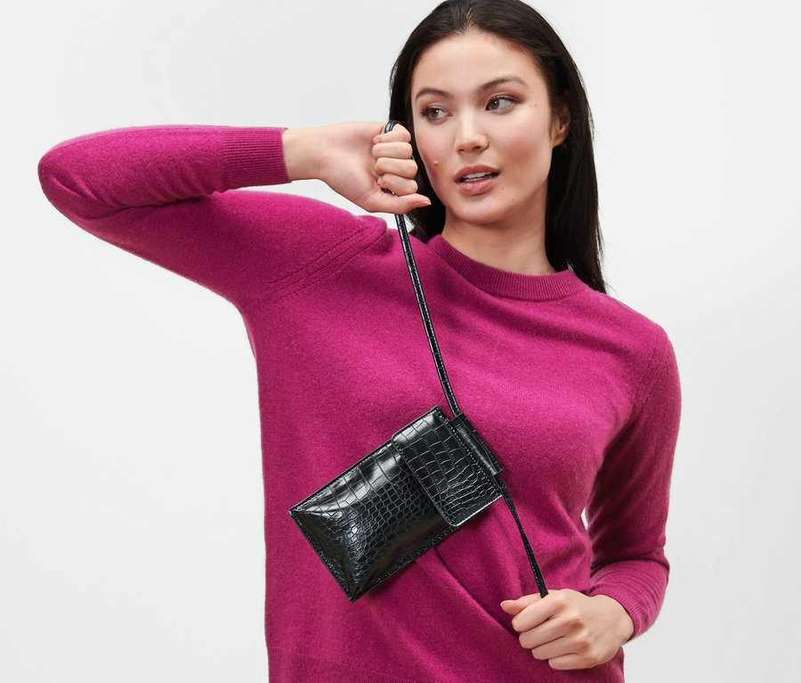 Femme posant avec un mini sac noir.