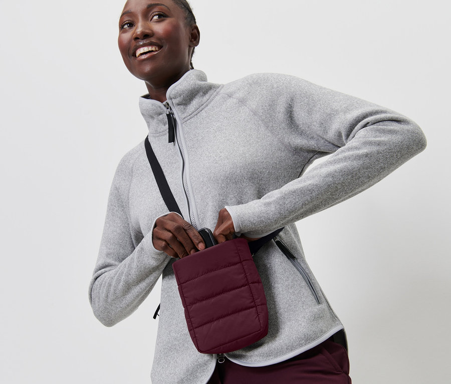 Une femme en polaire grise met un smartphone dans une pochette isolante.