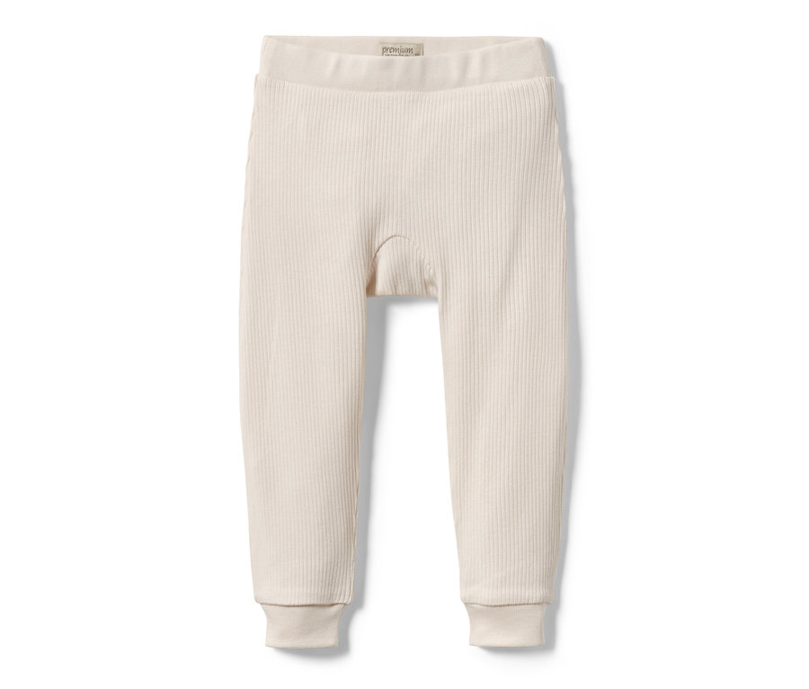 Un pantalon en maille beige pour bébés est posé sur un fond blanc.