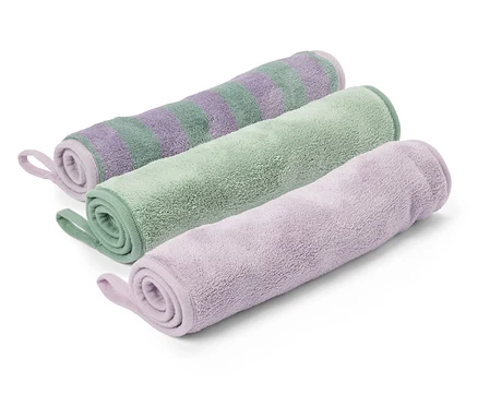 Trois débarbouillettes enroulées, rayées violettes, vertes et violettes, sont posées sur un fond blanc.