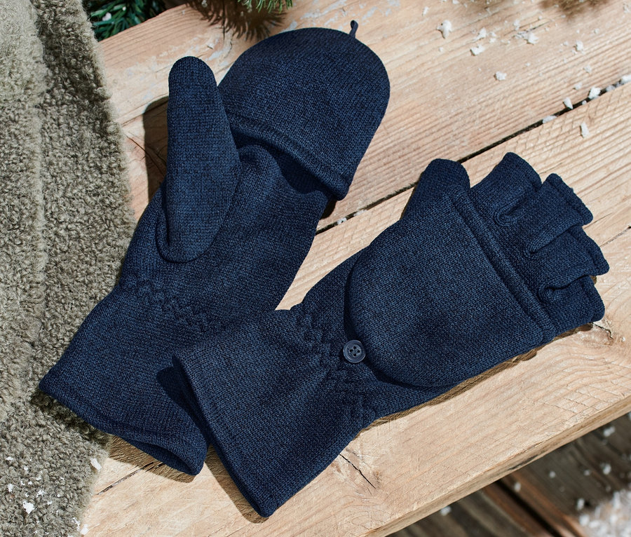 Deux mitaines avec moufles amovibles en maille polaire bleues sont posées sur un banc en bois. À côté se trouve une couverture marron et des aiguilles de sapin sont visibles.