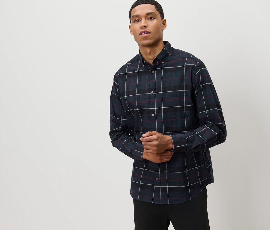 Un homme pose en chemise de flanelle bleu marine.