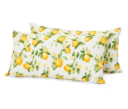 Deux oreillers blancs avec un motif de citrons, de feuilles et de fleurs sont superposés.