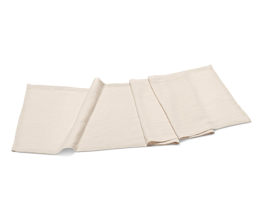 Un chemin de table en mousseline beige est plié sur un fond blanc.