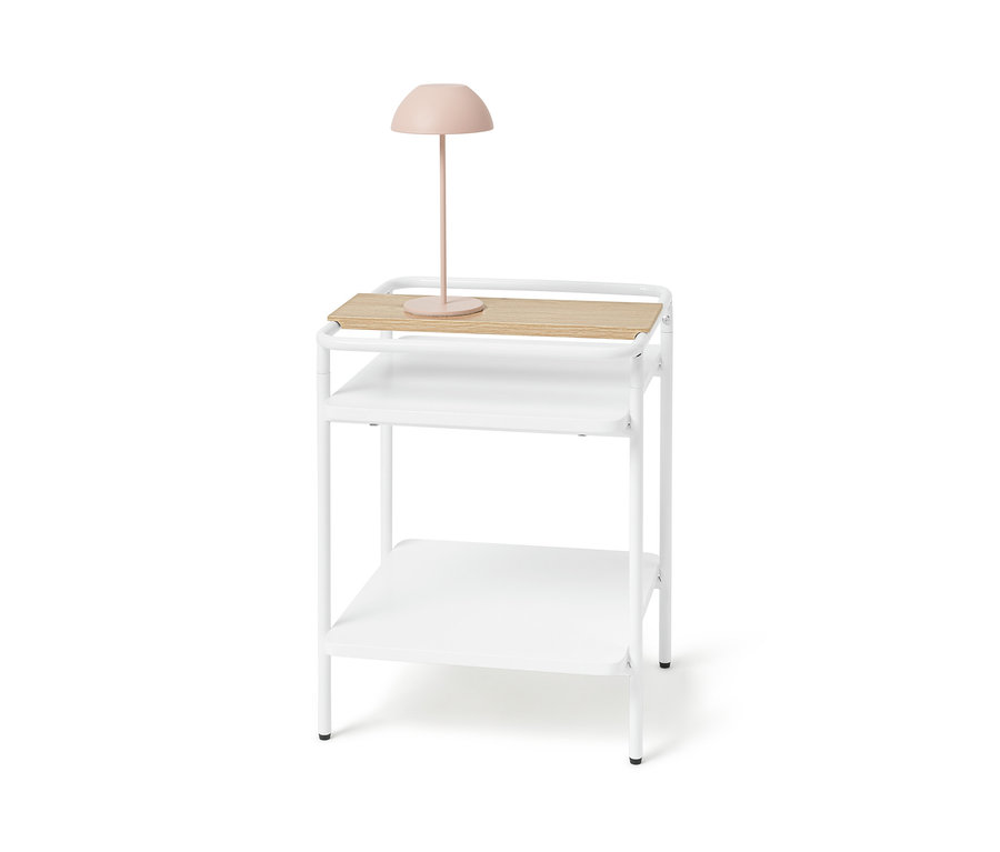 Table d’appoint blanche avec plateau en bois clair et lampe rose.