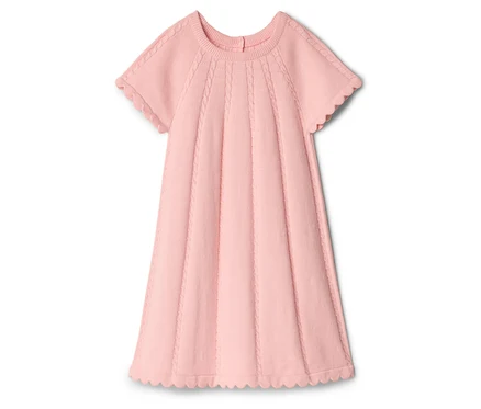 Une robe rose à manches courtes et à ourlet ondulé est posée sur un fond blanc.