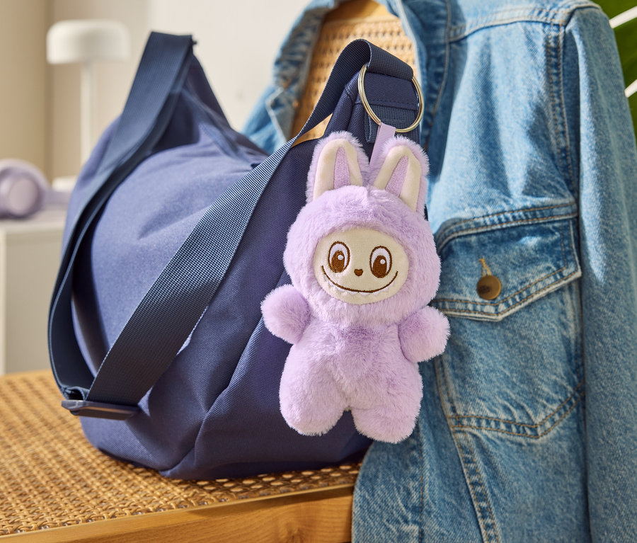 Un sac bleu avec le porte-clés «
Tchibobo
» accroché à une veste en jean.