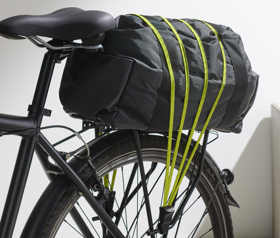 Un sac noir est fixé à un vélo à l'aide d'une sangle de vélo.