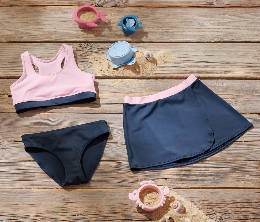 Ensemble de bikinis pour enfants et jouets sur une surface en bois.