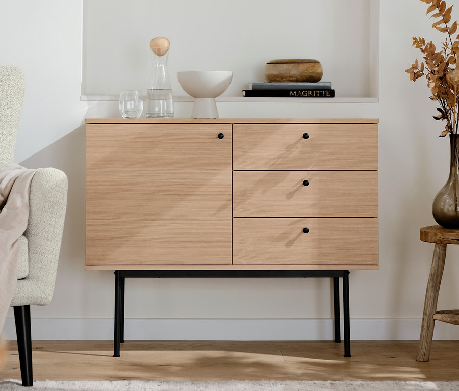 Dans le salon, une console »Finnsbo« avec des tiroirs. Des étagères avec des décorations sont au-dessus.