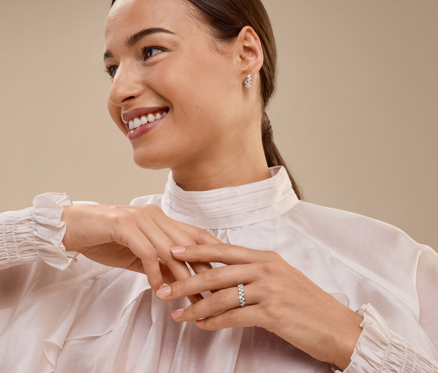 Femme souriante portant une bague et des boucles d'oreilles.