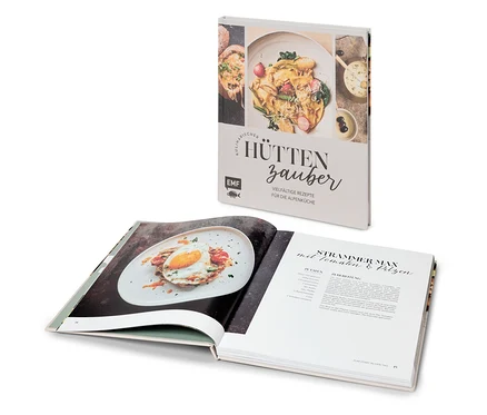 Livre de cuisine ouvert avec une recette pour "Strammer Max" et livre "Kulinarischer Hüttenzauber" derrière.