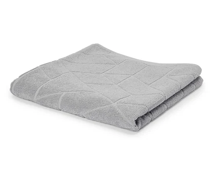 Une serviette gris clair pliée avec un motif géométrique est posée sur un fond blanc.