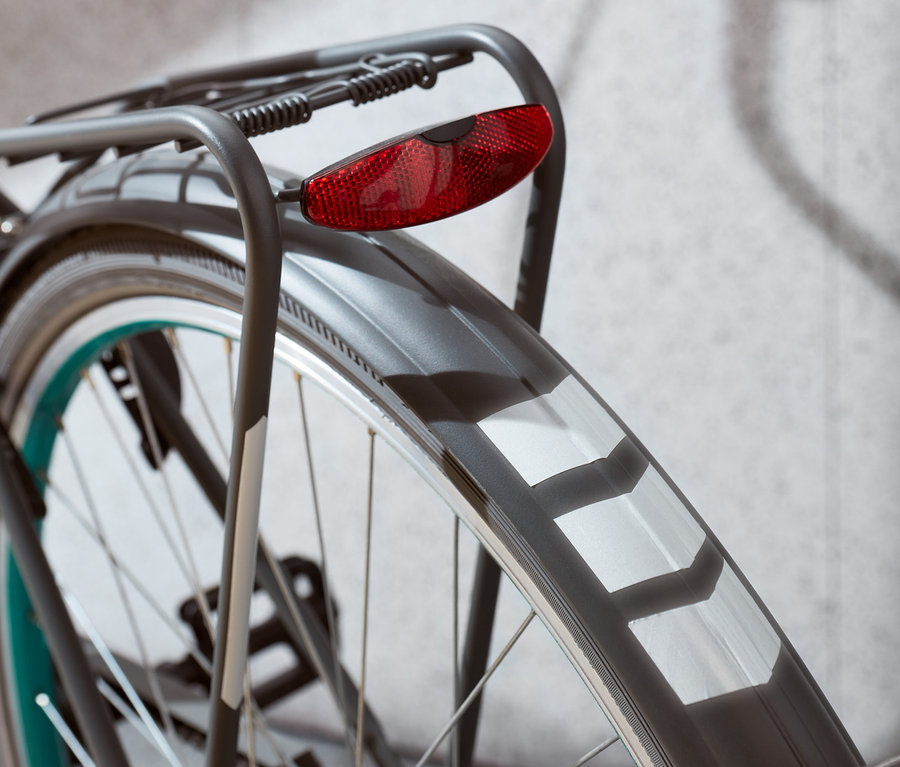 Gros plan de la roue arrière d'un vélo avec un feu rouge et des autocollants réfléchissants.
