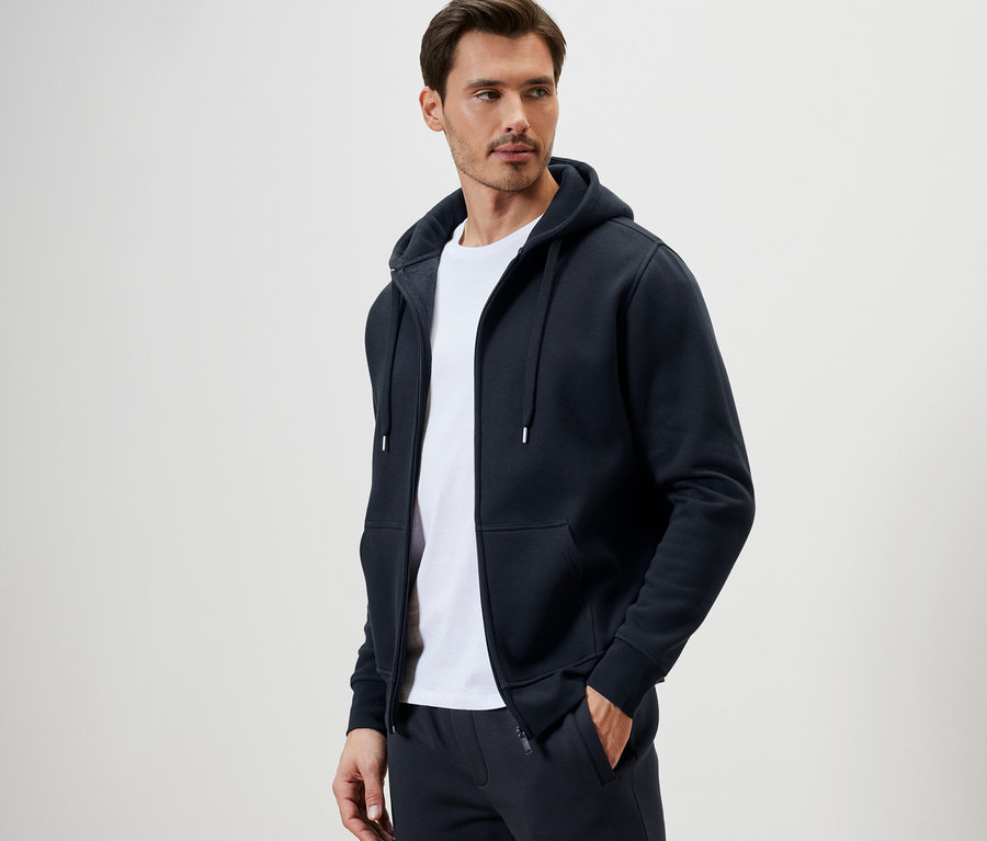 Un homme portant une veste à capuche et un t-shirt blanc.