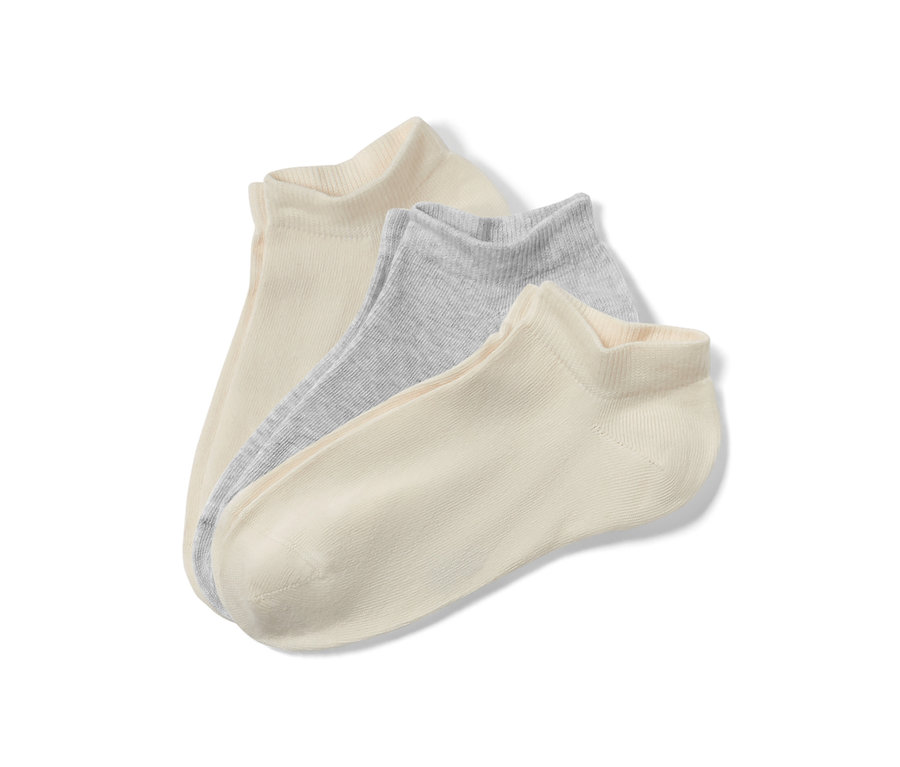 Gros plan de trois paires de socquettes pour enfants beiges et gris clair.
