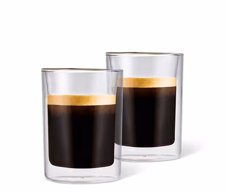 Deux verres à café crème remplis de café avec de la mousse sur fond blanc.