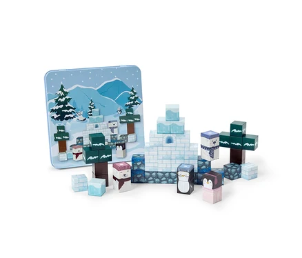 Un ensemble de blocs de construction colorés arrangés pour former une scène hivernale. Des blocs blancs et bleu clair créent des igloos et des formations de glace, tandis que des blocs verts et marron représentent des sapins. Plusieurs blocs présentent des visages d'ours polaires et de pingouins. Une boîte en étain bleu clair avec une illustration de paysage hivernal assortie se trouve en arrière-plan.