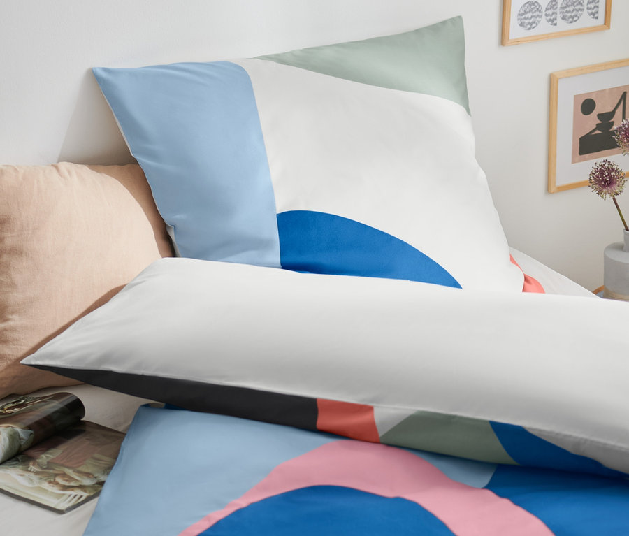 Gros plan sur une parure de lit en coton de qualité supérieure, de taille standard et grande, avec un motif géométrique bleu, vert et rose.