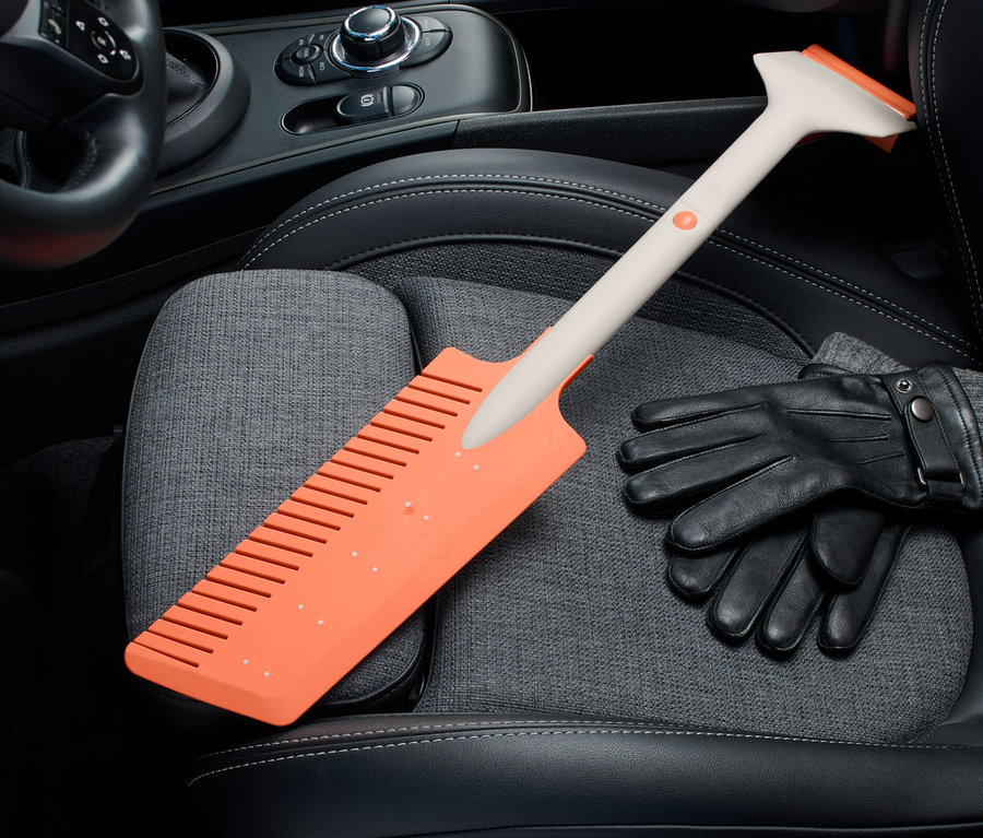 Un grattoir à glace orange pour voiture à enficher est posé sur un siège auto à côté de gants noirs.