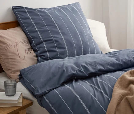 Parure de lit en jersey d'hiver avec une housse bleue à rayures verticales sur l'oreiller et la couette.