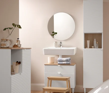 Une salle de bain comprend un Badhochschrank »SONARI« mit Türen, un Waschbeckenunterschrank »SONARI« mit Schubladen et une Badkommode »SONARI« mit Türen. Un tapis de bain confortable d'environ 60 x 100 cm se trouve devant un Tritthocker aus Massivholz. Deux serviettes de toilette bleues de qualité supérieure sont posées sur le Waschbeckenunterschrank.