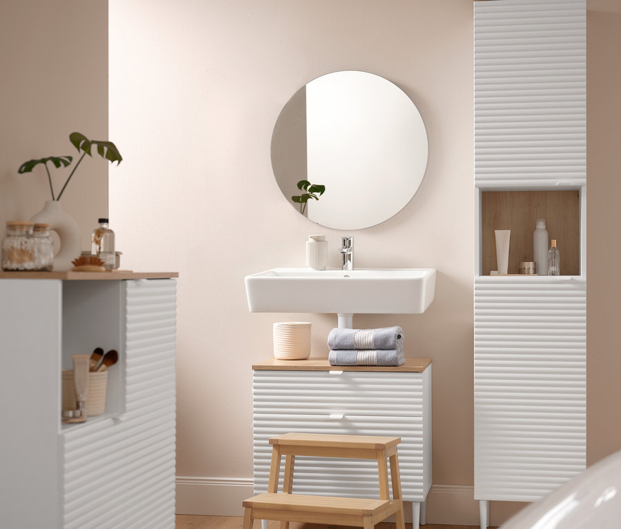 Une salle de bain comprend un Badhochschrank »SONARI« mit Türen, un Waschbeckenunterschrank »SONARI« mit Schubladen et une Badkommode »SONARI« mit Türen. Un tapis de bain confortable d'environ 60 x 100 cm se trouve devant un Tritthocker aus Massivholz. Deux serviettes de toilette bleues de qualité supérieure sont posées sur le Waschbeckenunterschrank.