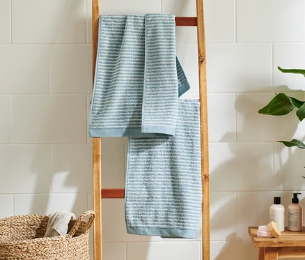 Deux linges de toilette de haute qualité bleu clair et bleu sont suspendus à une échelle en bois dans la salle de bain.