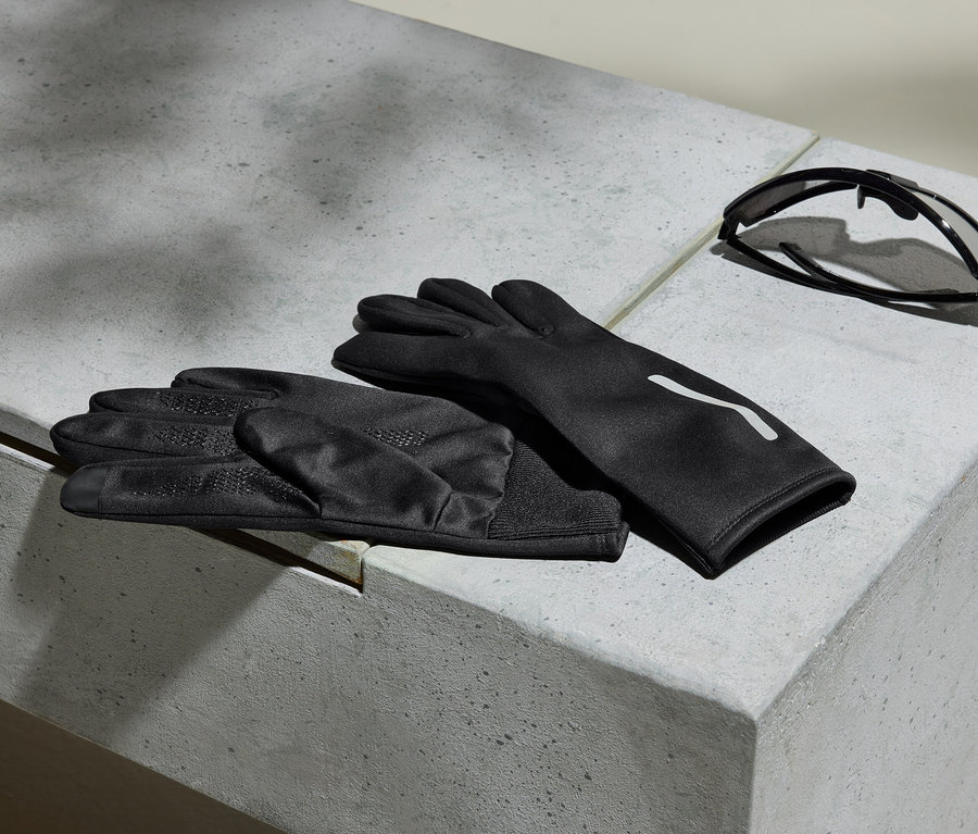 Des gants noirs et des lunettes de soleil reposent sur une surface en béton gris.