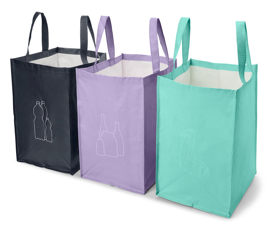 Trois sacs de courses en tissu sont alignés. Les sacs sont bleu foncé, violet et bleu clair et ont des images blanches d'articles recyclés.