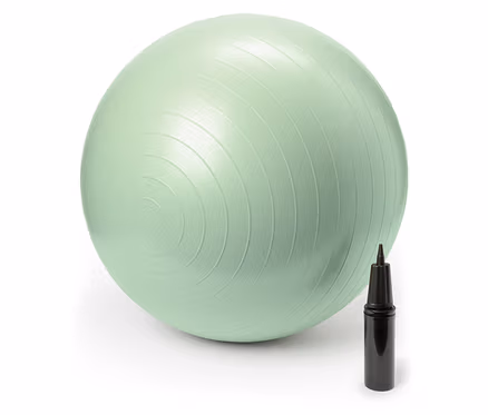 Un ballon de gymnastique vert pastel est posé à côté d'une pompe à main noire.
