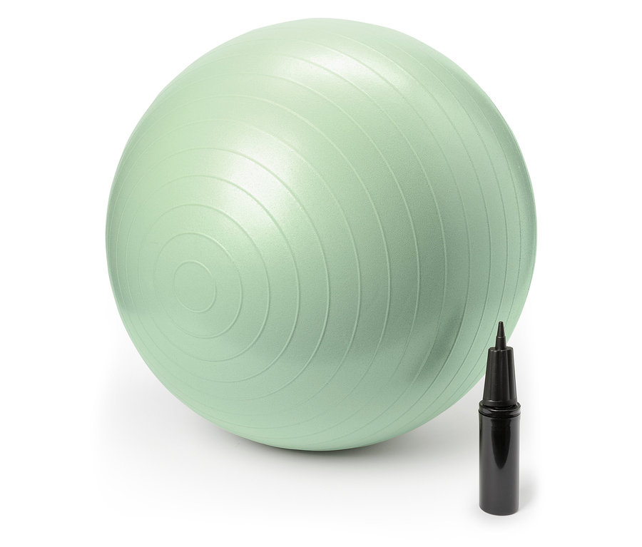 Un ballon de gymnastique vert pastel est posé à côté d'une pompe à main noire.