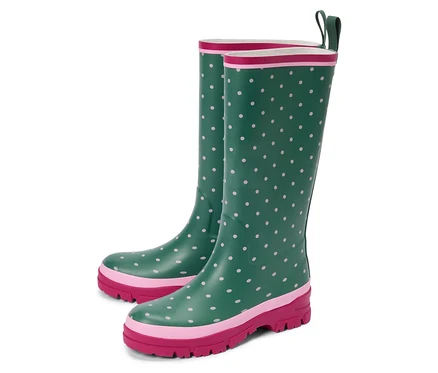 Deux bottes en caoutchouc vertes à pois roses se tiennent sur un fond blanc.