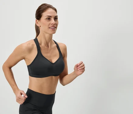 Femme courant portant un soutien-gorge de sport noir et un legging.