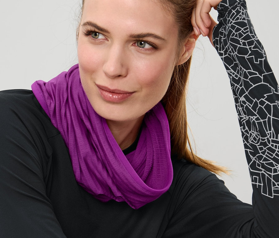 Femme assise portant un foulard multifonction violet.