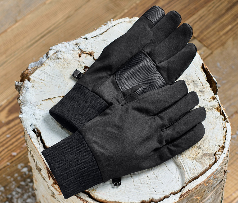 Des gants en softshell noirs sont posés sur une bûche.