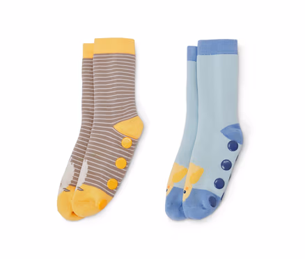 Deux paires de chaussettes anti-dérapantes pour enfant. Une paire est rayée marron et blanc avec des détails jaunes et une image d'oiseau, l'autre paire est bleu clair avec une image de girafe et des points bleu foncé.
