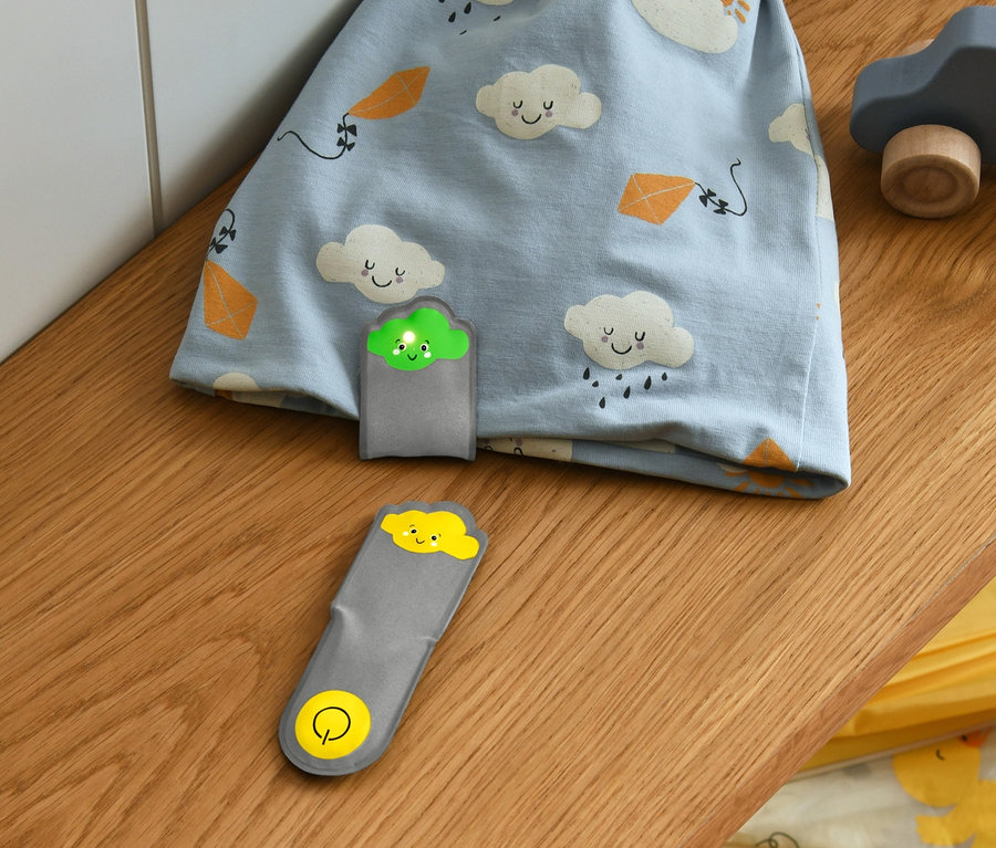 Un bonnet bleu à motifs de nuages et 2 lumières magnétiques à LED « nuages » sont posés sur une étagère.