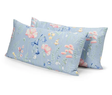 Deux oreillers à motifs floraux sur fond bleu sont placés l'un sur l'autre.